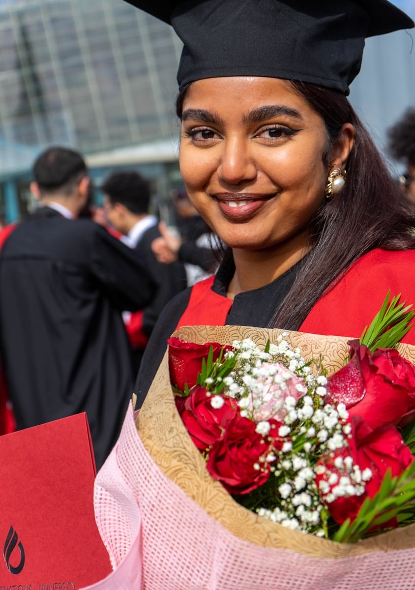 a woman in a graduation gown holding a bouquet of flowers