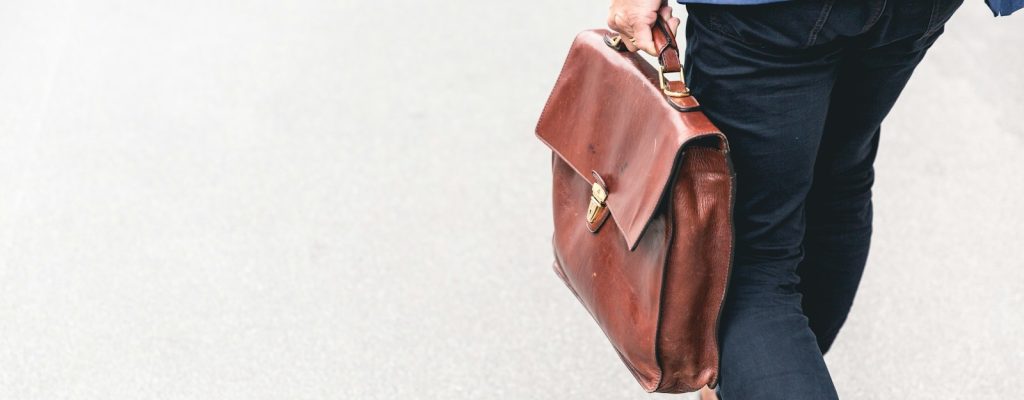 person walking holding brown leather bag