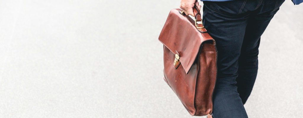 person walking holding brown leather bag